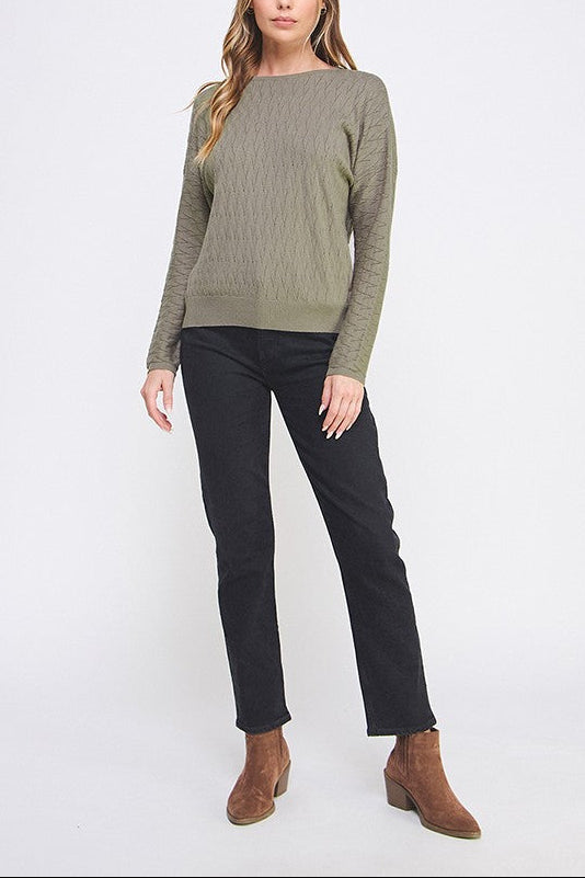 Woman wearing a green sweater and black pants on a white background