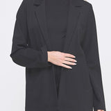 Woman wearing a black blazer over a black top on a white background