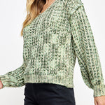 Woman wearing a green patterned sweater on a white background