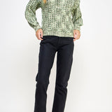 Woman wearing a green patterned sweater and black pants on a white background