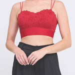 Woman wearing a red lace top and black pants on a white background
