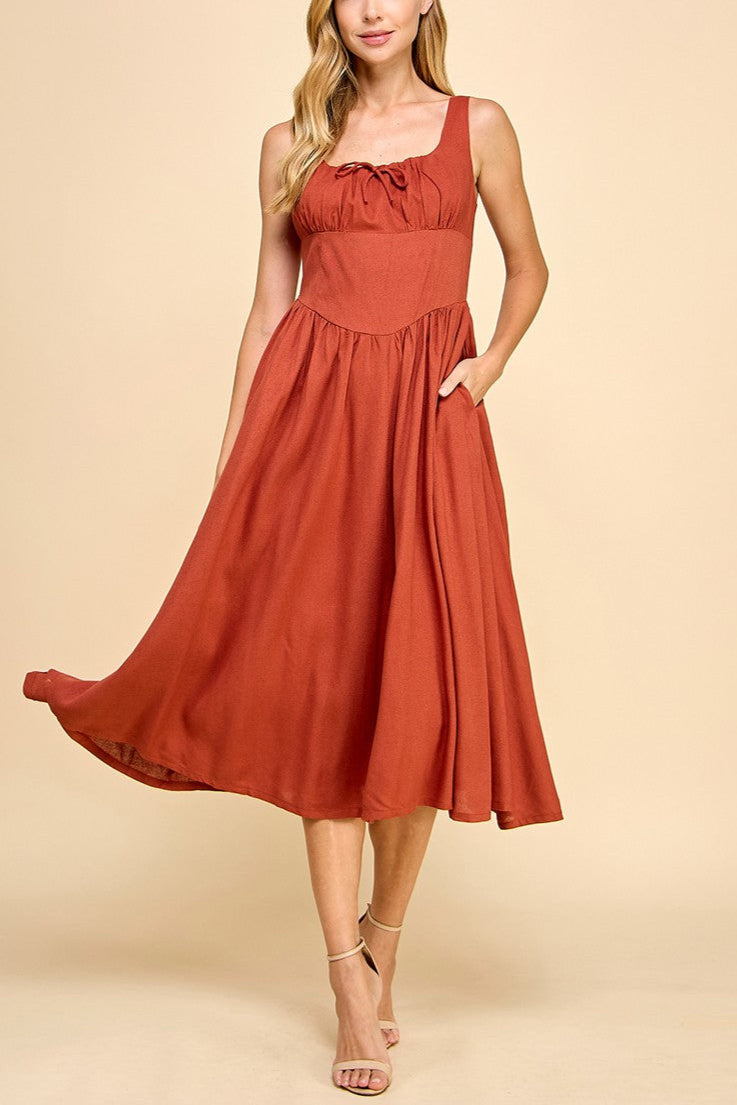 Woman wearing a rust-colored dress against a beige background