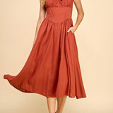 Woman wearing a rust-colored dress against a beige background