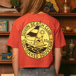 Woman wearing red Duvin Beach Club cropped t-shirt with circular logo featuring surfer design