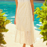 Woman in a white dress standing by a pool with greenery around