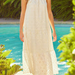 Woman in a white dress standing by a pool with greenery around