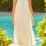 Woman in a white dress standing by a pool with greenery around