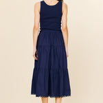 Woman wearing a navy blue sleeveless dress with a beige background