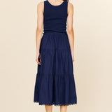 Woman wearing a navy blue sleeveless dress with a beige background