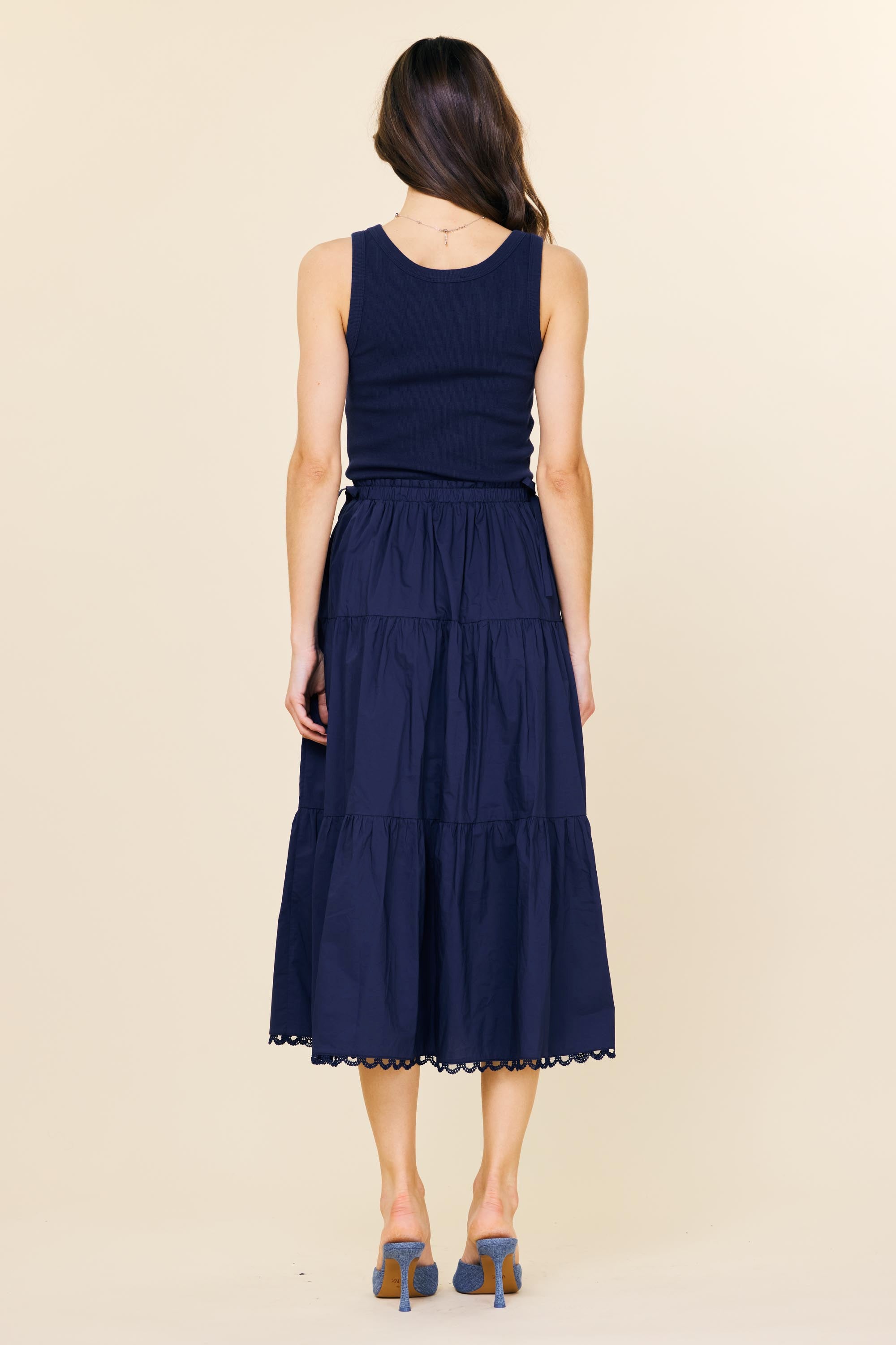 Woman wearing a navy blue sleeveless dress with a beige background