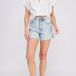 Woman wearing a white blouse and denim shorts on a white background