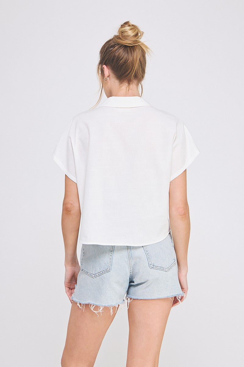 Person wearing a white shirt and light blue denim shorts on a plain background