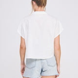 Person wearing a white shirt and light blue denim shorts on a plain background