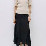 Woman wearing a beige sweater and black skirt on a white background