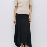 Woman wearing a beige sweater and black skirt on a white background