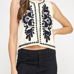 Woman wearing a sleeveless top with black floral patterns on a white background