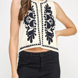 Woman wearing a sleeveless top with black floral patterns on a white background
