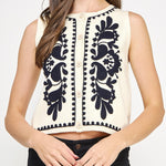 Woman wearing a sleeveless top with black floral patterns on a white background