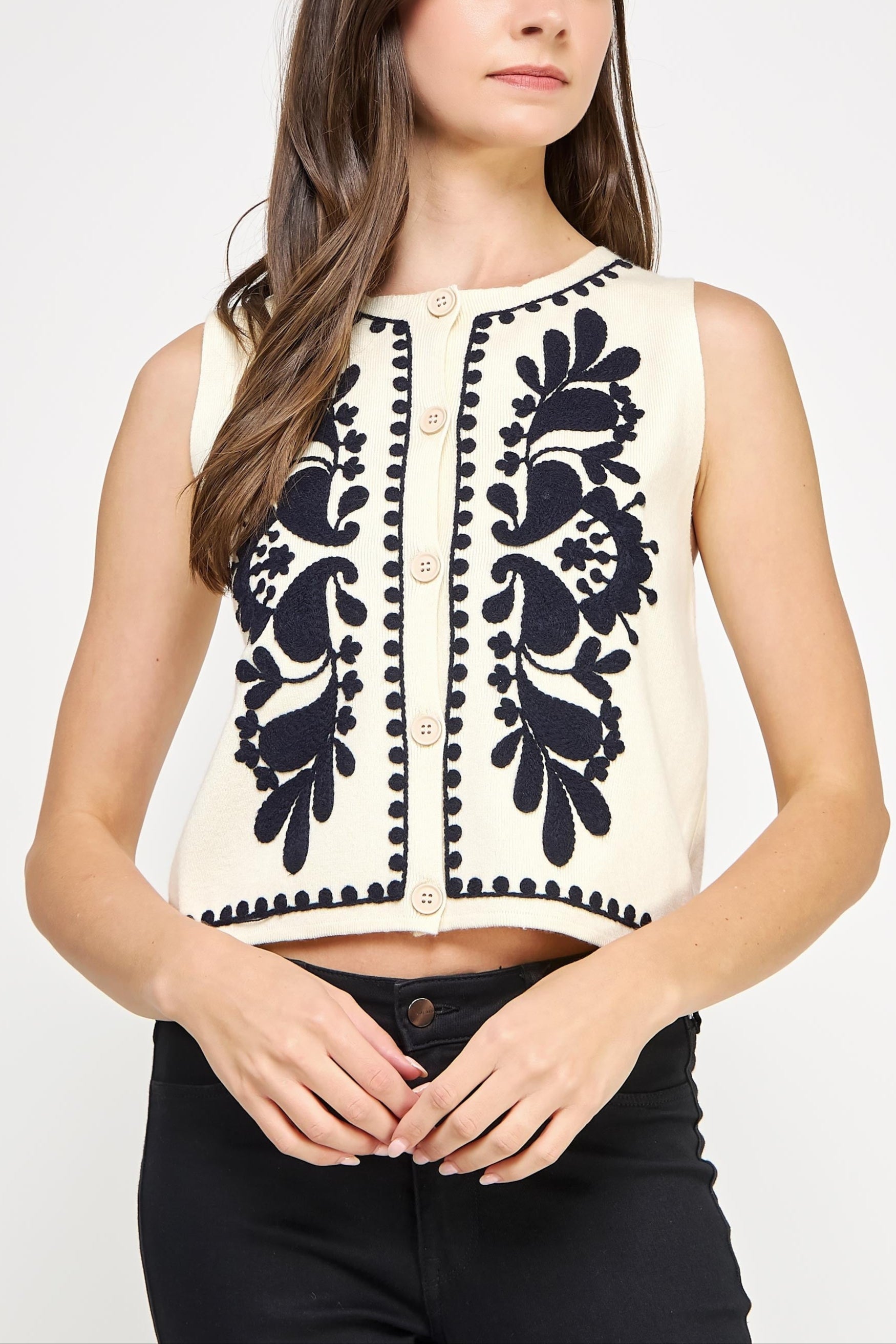 Woman wearing a sleeveless top with black floral patterns on a white background