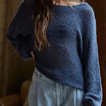 Woman wearing a blue sweater and light blue jeans indoors.