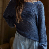 Woman wearing a blue sweater and light blue jeans indoors.