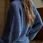 Woman wearing a blue sweater in a wooden interior setting