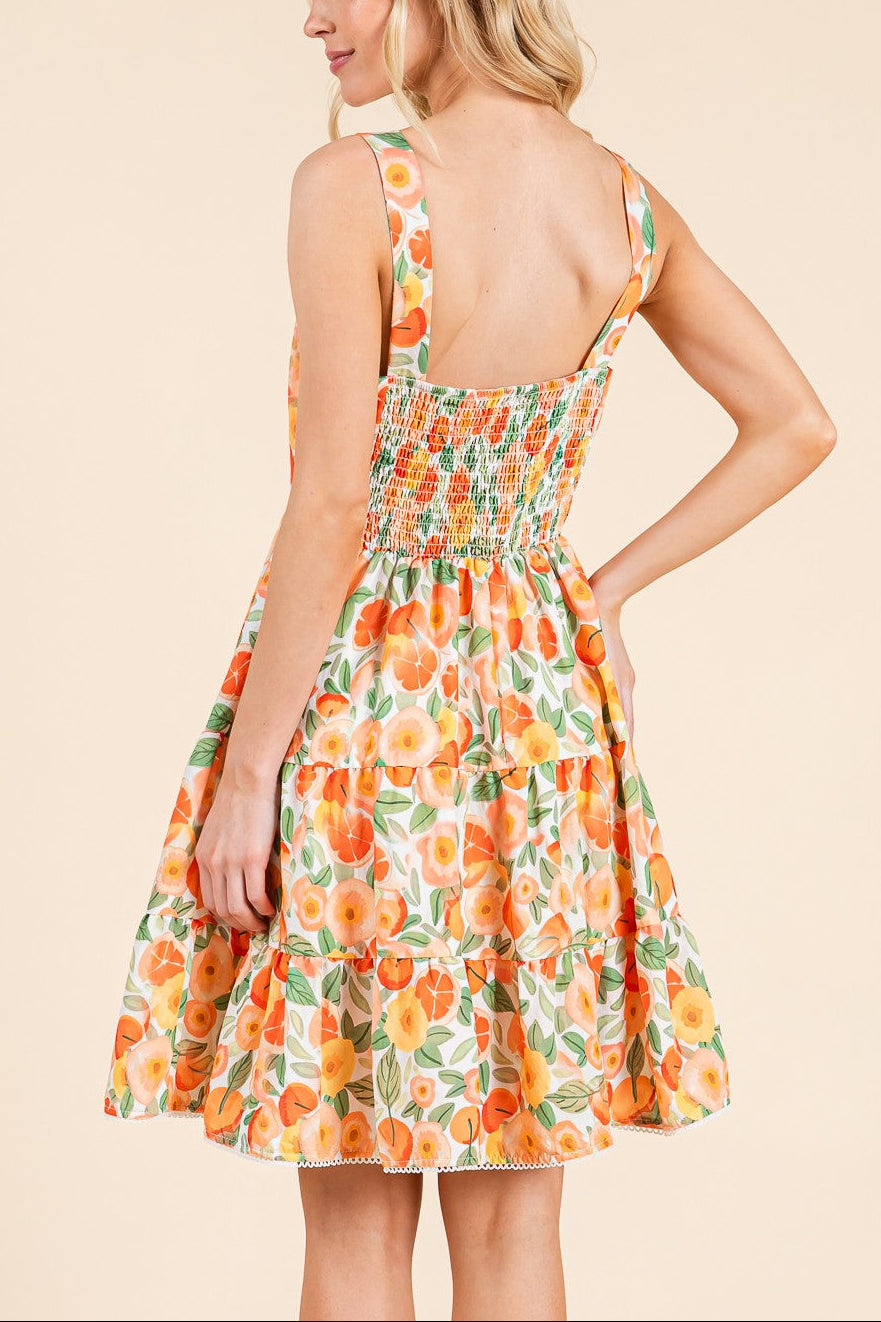 Woman wearing a floral dress with an orange and green pattern on a beige background