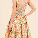 Woman wearing a floral dress with an orange and green pattern on a beige background