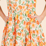Dress with a floral pattern featuring orange flowers and green leaves on a beige background