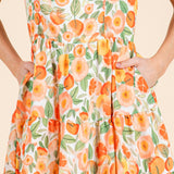 Dress with a floral pattern featuring orange flowers and green leaves on a beige background