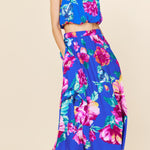 Woman wearing a colorful floral two-piece outfit on a beige background