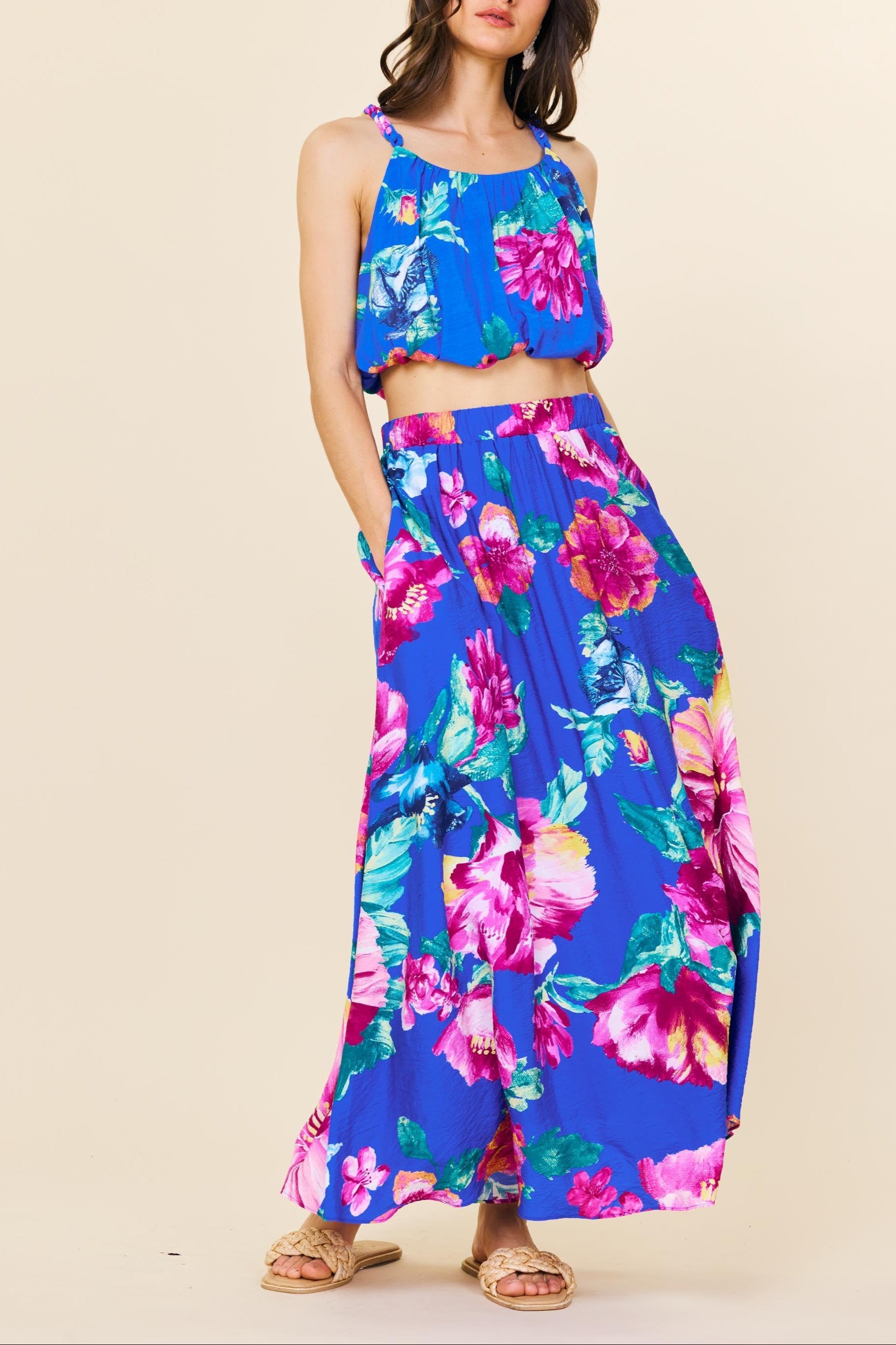 Woman wearing a colorful floral two-piece outfit on a beige background