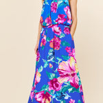 Woman wearing a colorful floral dress against a beige background