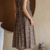 Woman wearing a patterned dress standing in a room with decorative vases and a textured wall.