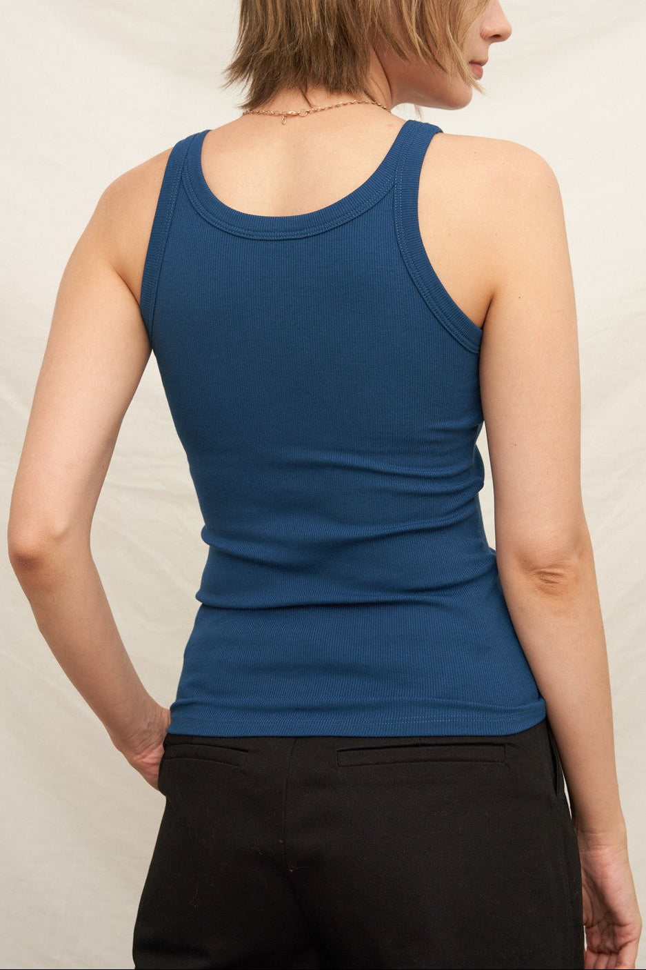 Person wearing a blue tank top against a plain background