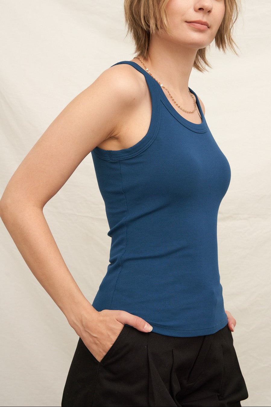 Woman wearing a blue tank top against a plain background