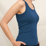 Woman wearing a blue tank top against a plain background