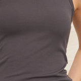 Close-up of a person wearing a dark ribbed tank top against a neutral background
