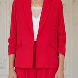 Woman wearing a red suit with a white top in an elegant room.