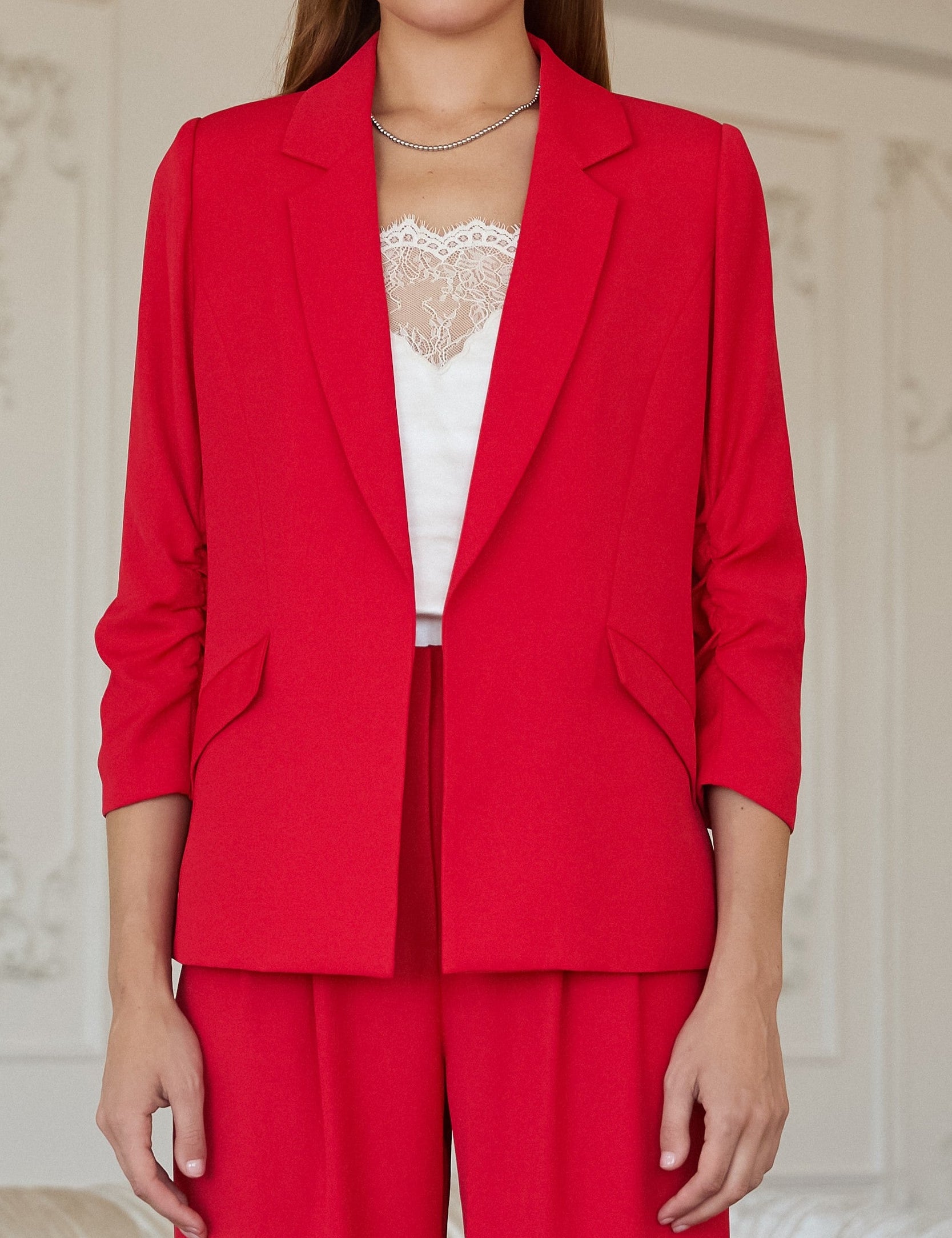 Woman wearing a red suit with a white top in an elegant room.