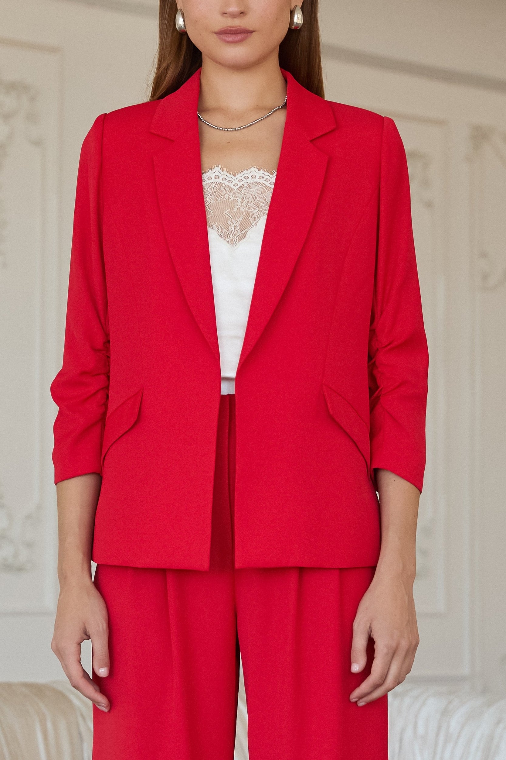 Woman wearing a red suit with a white top in an elegant room.