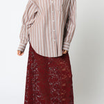 Woman wearing a striped shirt and red lace skirt on a white background