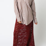 Woman wearing a striped shirt and long burgundy skirt on a white background