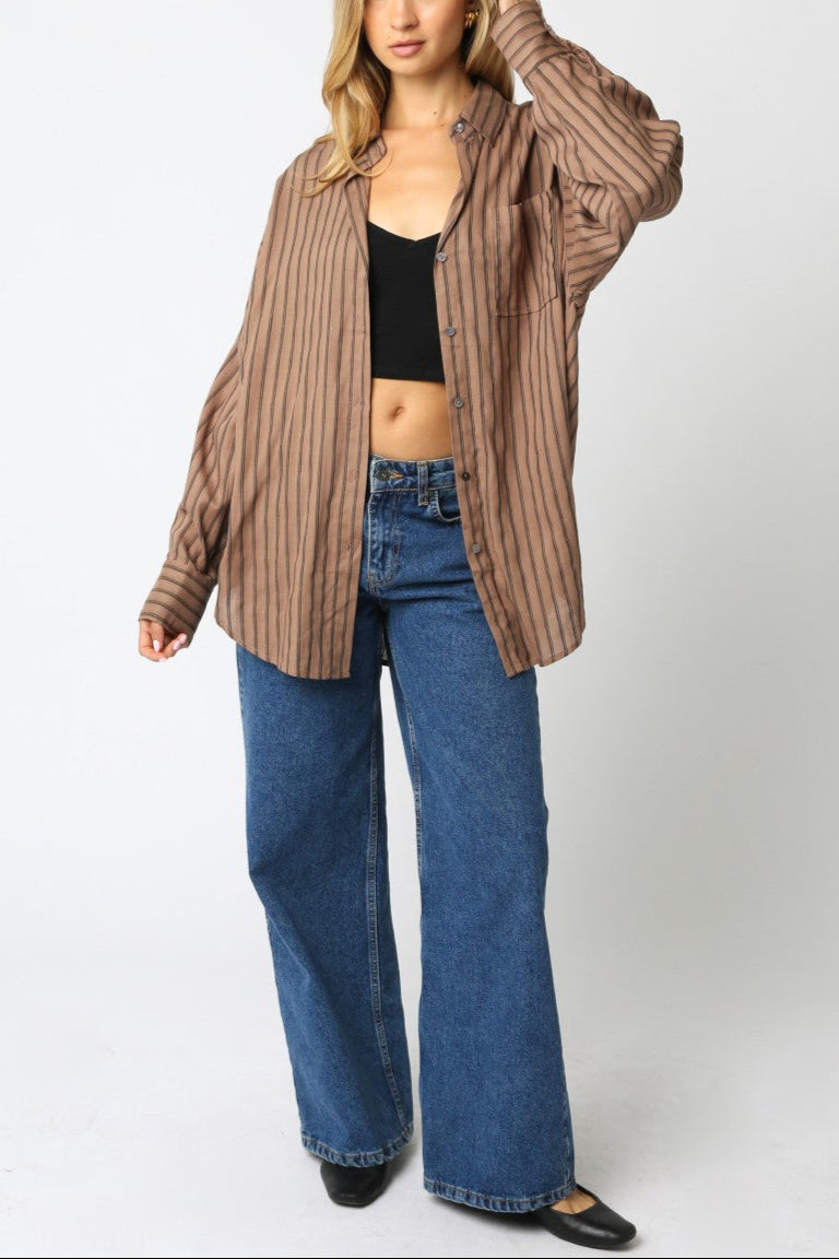 Woman wearing a striped shirt, black top, and blue jeans on a white background