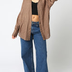 Woman wearing a striped shirt, black top, and blue jeans on a white background