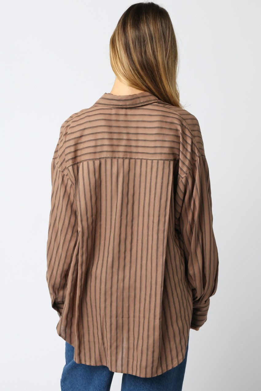 Woman wearing a brown striped shirt against a white background