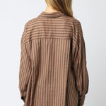 Woman wearing a brown striped shirt against a white background
