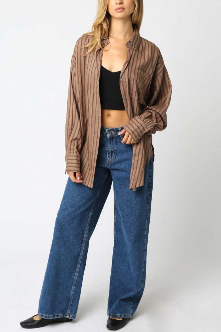 Woman wearing a brown striped shirt and blue jeans on a white background