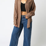 Woman wearing a brown striped shirt and blue jeans on a white background