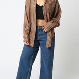 Woman wearing a brown striped shirt and blue jeans on a white background